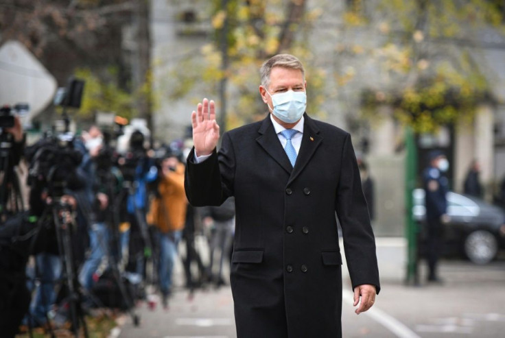 Romanian President Klaus Iohannis waves at a polling station before voting in Bucharest during Sunday's parliamentary elections