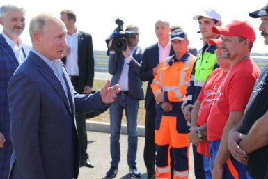 Russian President Vladimir Putin (2nd L) accompanied by Transport Minister Yevgeny Ditrikh (L) meets with road workers during a ceremony to launch a traffic of the Tavrida federal highway, in Crimea, on August 27, 2020