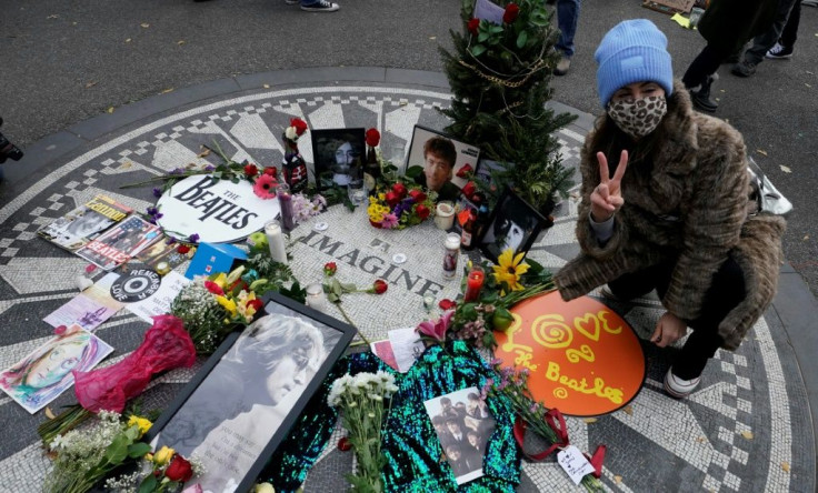 A woman flashes a peace sign as mourners gather on the 40th anniversary of John Lennon's death in New York's Central Park, across the street from the site of his murder