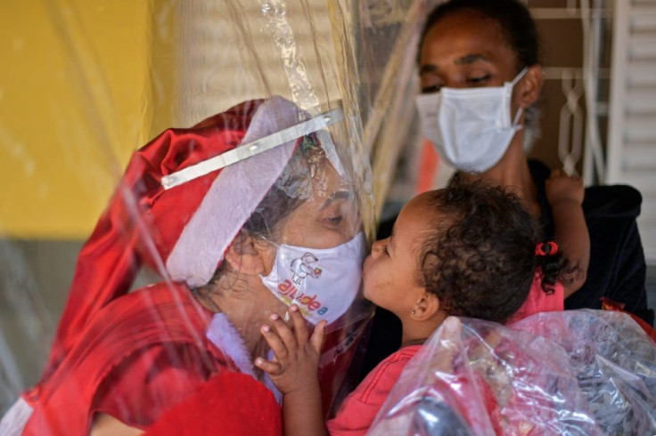 A needy child kisses volunteer Fatima Sanson, dressed up as Mrs. Claus, in Belo Horizonte, Minas Gerais state, Brazil on December 7, 2020