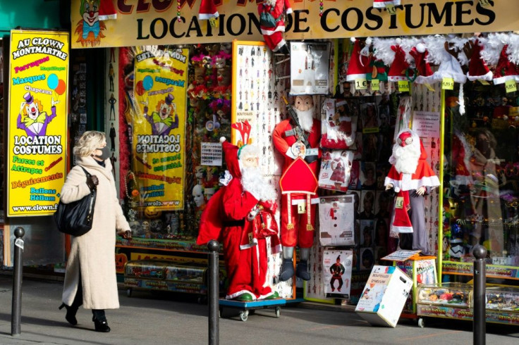 A woman walks past a costume rental store, with Santa Claus outfits outside, on December 10, 2020 in Paris as France is on a second lockdown in a bid to contain the spread of Covid-19 pandemic caused by the novel coronavirus