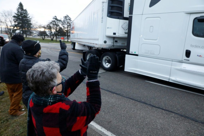 People cheer as trucks carry the first shipment of the Covid-19 vaccine to leave Pfizer's facility in Michigan