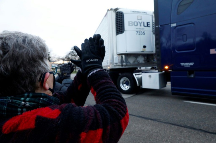 Susan Deur cheers as trucks carrying the first shipment of the Covid-19 vaccine that is being escorted by the US Marshals Service, leave Pfizer's Global Supply facility in Kalamazoo, Michigan