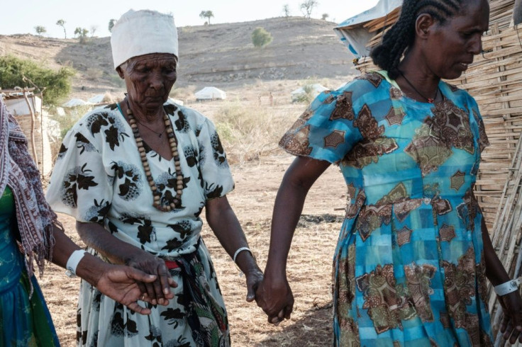 Ethiopian Asafu Alamaya (C), a 80-year-old blind woman who fled the Tigray conflict, is guided by her daughter at the Um Raquba refugee camp in Sudan's eastern Gedaref state