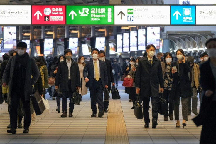 Commuters wearing face masks walk along a concourse at Shinagawa station in Tokyo