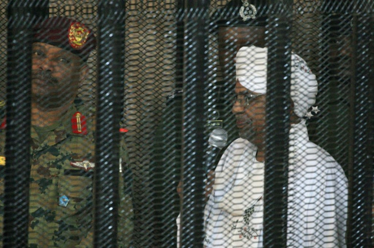 Al-Bashir stands in a defendant's cage during the opening of his corruption trial in Khartoum in August last year