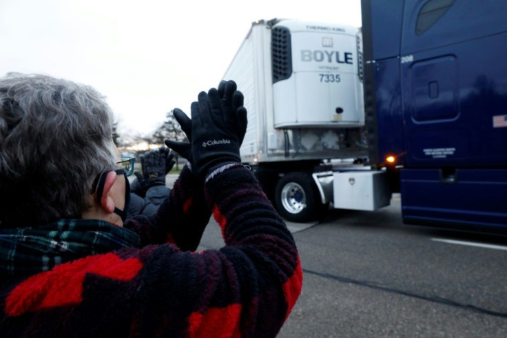 A bystander cheers as trucks carrying the first shipment of Covid-19 vaccine leave Pfizer's global supply facility in Kalamazoo, Michigan