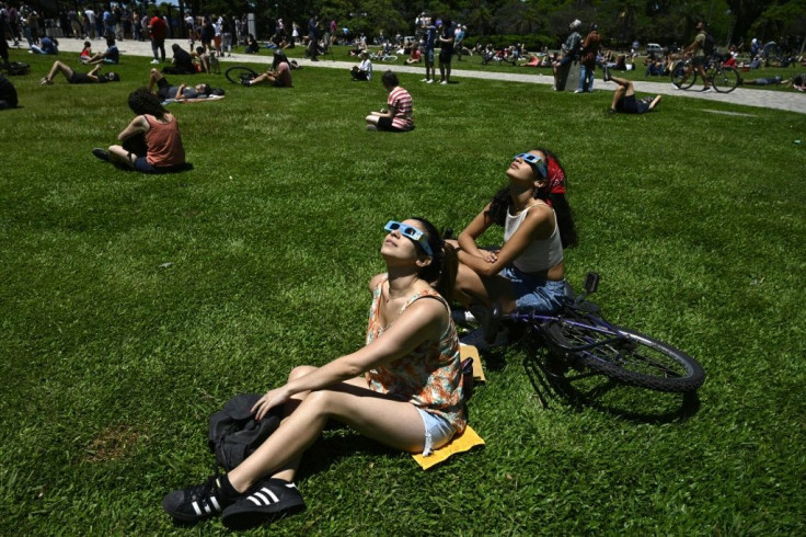 People watch the solar eclipse in front at the Galileo Galilei planetarium in Buenos Aires