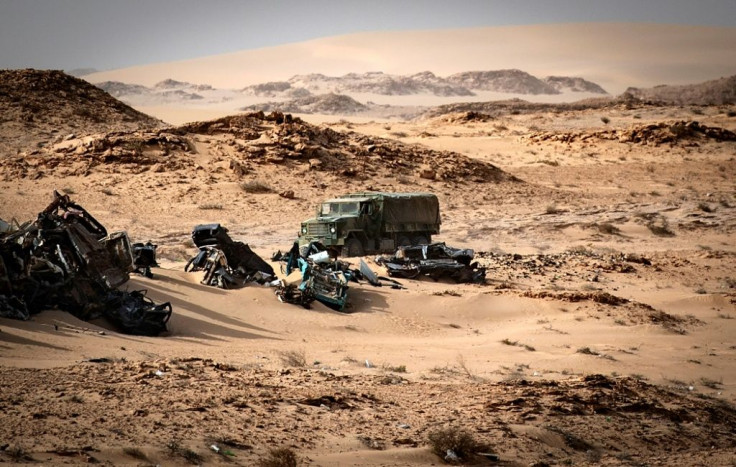 A Moroccan military truck passes vehicle wreckage in Western Sahara on November 24, after Morocco sent troops into a UN-patrolled buffer zone to reopen a road blocked by a group of separatists