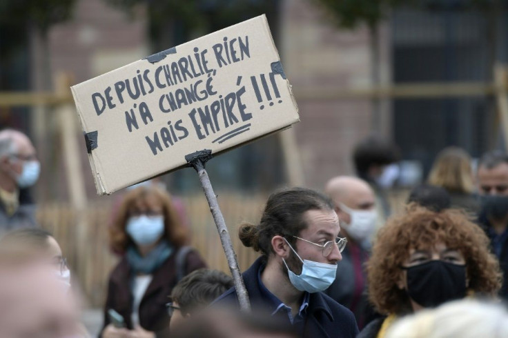 A man holds a placard reading "Nothing changed since Charlie" at a demonstration for schoolteacher Samuel Paty two days after he was beheaded by an attacker