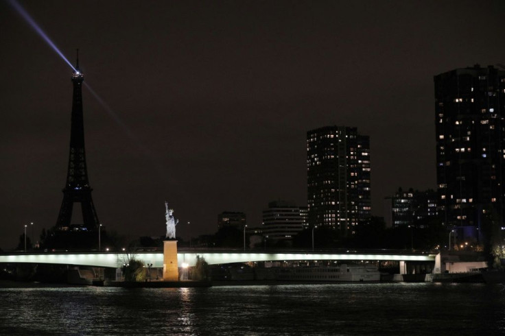 The statue of liberty replica in Paris is illuminated here against a dark background.