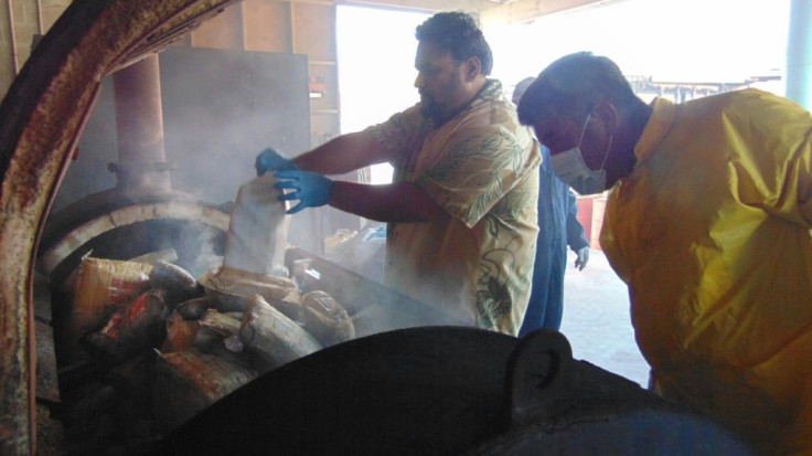 Marshall Islands Police Captain Eric Jorban, (L), empties one-kilo packages of cocaine into an incinerator in Majuro  in the Marshall Islands