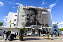 People queue up outside the main post office on Mohamed Bouazizi Square, its facade displaying a picture of Bouazizi, who set himself on fire ten years ago