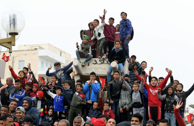 Children chant slogans from atop a sculpture of Mohamed Bouazizi's cart in the square named after him in Sidi Bouzid on Thursday