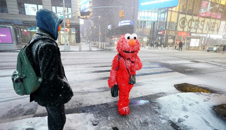 A person in an Elmo costume stands under the snow in Times Square in New York City, December 16, 2020