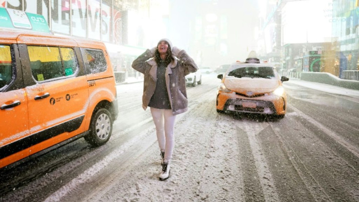 A tourist stands under the snow in Times Square in New York City, December 16, 2020