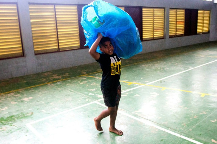 A Fijian boy carries a bag to a temporary shelter to avoid strong damaging winds from super cyclone Yasa in the capital city of Suva on December 17, 2020