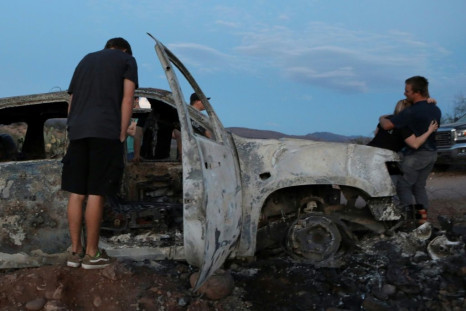 This November 5, 2019 photo shows relatives looking at a burned car that had been carrying some of the nine Mormon women and children who were gunned down