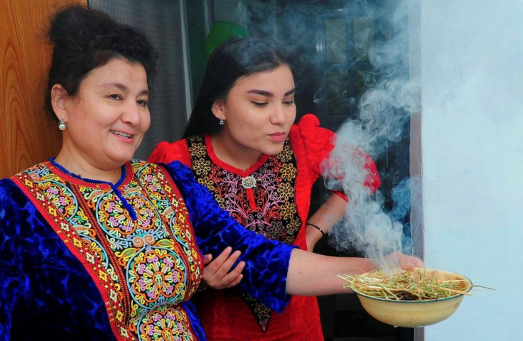 Turkmen women wearing traditional dress demonstrate how to fumigate a house with the smoke of burning wild rue