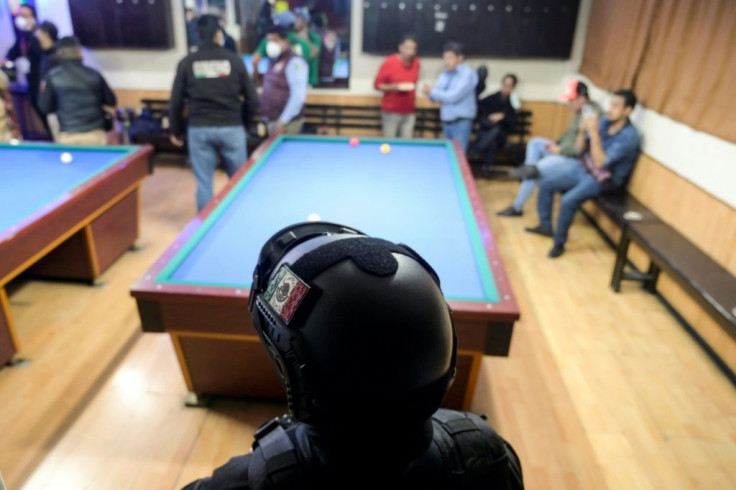 A Mexican police officer stands guard inside a billiard hall during a local government operation against illegal gatherings