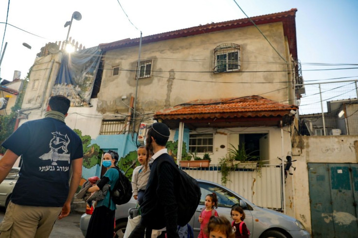 Israeli settlers walk in front of a home inhabited by Palestinians, in the predominantly Arab neighbourhood of Silwan in east Jerusalem