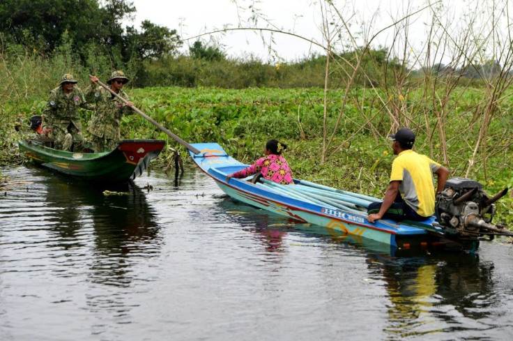 Rangers (L) stop a fishing boat for questioning on the Tonle Sap. They warn that animal habitats are under imminent threat, including a huge bird sanctuary where desperate fishermen are seeking new places to cast their nets