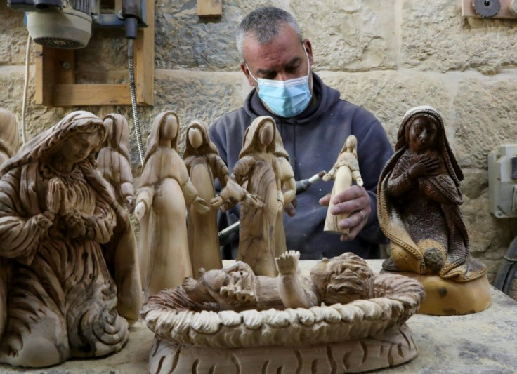 A Palestinian carpenter carves religious statues and figurines from olive wood at a shop near the Church of the Nativity in the West Bank city of Bethlehem