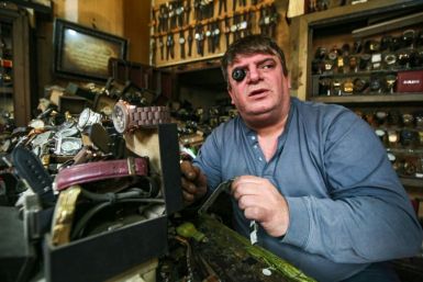 Watch repairman Youssef Abdelkarim sits wearing a jewellery magnifier as he fixes a timepiece at his workshop on Rasheed Street in Iraq's capital Baghdad