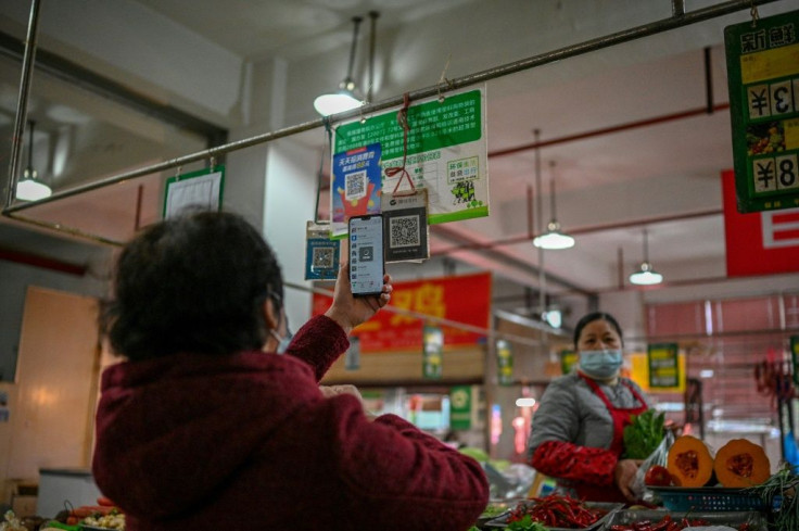 A woman uses her mobile phone to pay for produce at a market in Chengdu, the capital of China's Sichuan province