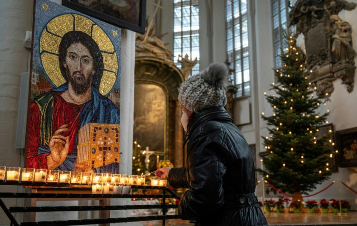 In Germany's capital Berlin, a worshipper lights a candle in St Mary's church ahead of an outdoor mass on Christmas Eve