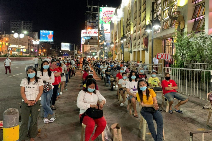 Catholic devotees attend a Christmas eve mass maintaining social distancing to prevent the spread of coronavirus, outside the Quiapo church in Manila