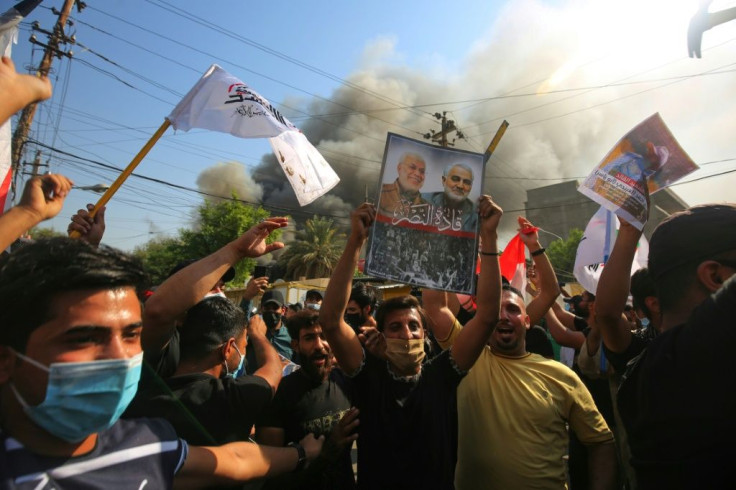 Iraqi demonstrators, supporters of the pro-Iranian Hashed al Shaabi, raise portraits of slain Iranian commander Qassem Soleimani and Iraqi paramilitary commander Abu Mahdi Al-Muhandis