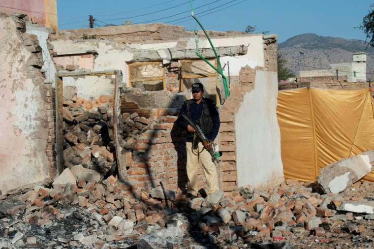 A policeman stands guard outside the Hindu temple destroyed by a Muslim mob