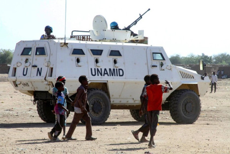 Sudanese children walk past an armoured vehicle of the United Nations and African Union peacekeeping mission (UNAMID) in Kalma Camp for internally displaced people in Nyala, the capital of South Darfur, on Wednesday