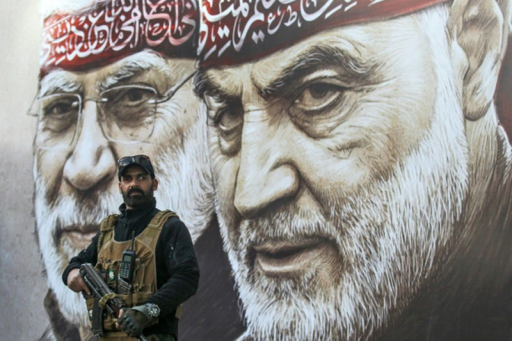 An Iraqi fighter of the largely pro-Iran Hashed al-Shaabi paramilitary force stands guard beneath portraits of slain Iranian Revolutionary Guards commander Qasem Soleimani (R) and Abu Mahdi al-Muhandis