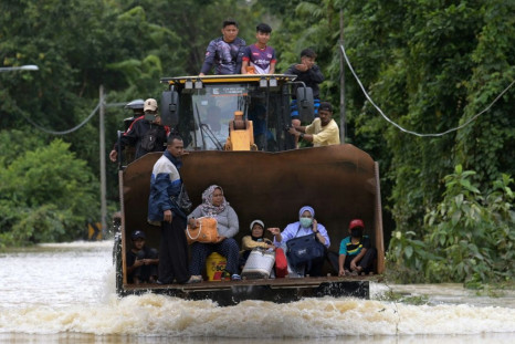 Residents ride a digger through floodwaters following heavy monsoon downpours in Lanchang in Malaysia's Pahang state