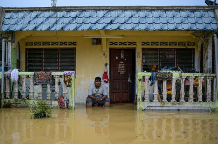 A resident sits outside his home, partially submerged in floodwaters, in Kuala Kaung, near Lanchang in Malaysia's Pahang state
