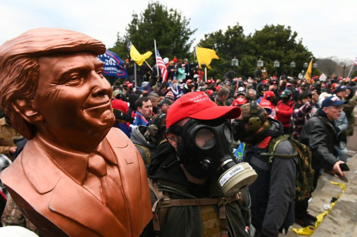 A supporter of US President Donald Trump wears a gas mask and holds a bust of him after he and hundreds of others stormed stormed the Capitol building