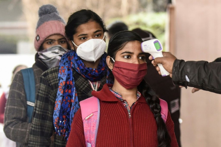 A worker checks the body temperature of a student at a government girls school in Amritsar, India