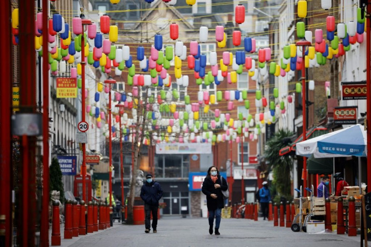 Pedestrians wear facemasks walking through London's Chinatown as the capital's mayor declares a flood of new cases has left the city at "crisis point"