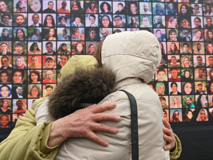 Grieving relatives in front of a huge screen displaying photos of the 176 people killed when a Ukraine International Airlines flight was downed a year ago. The first-year anniversary event was held at the site of a future memorial in Kiev