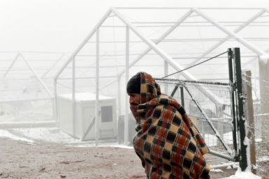 A migrant walks past what remains of the tents of the 'Lipa' migrant camp in Bosnia, two weeks after it burnt down. Hundreds of migrants are waiting for new shelters