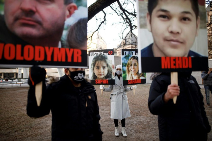 People hold signs with images of the victims of the downed Ukraine International Airlines flight PS752, as family and friends gather to take part in a march to mark the first anniversary, in Toronto, Ontario, Canada, on January 8, 2021