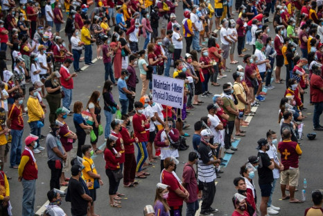 Ignoring official pleas to stay home because of the virus threat, Catholics wearing masks and face shields gathered along an avenue outside the Quiapo Church in Manila