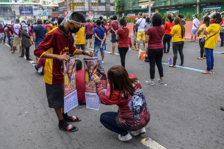 A Catholic devotee buys a calendar with the image of the Black Nazarene during mass on a street in Manila