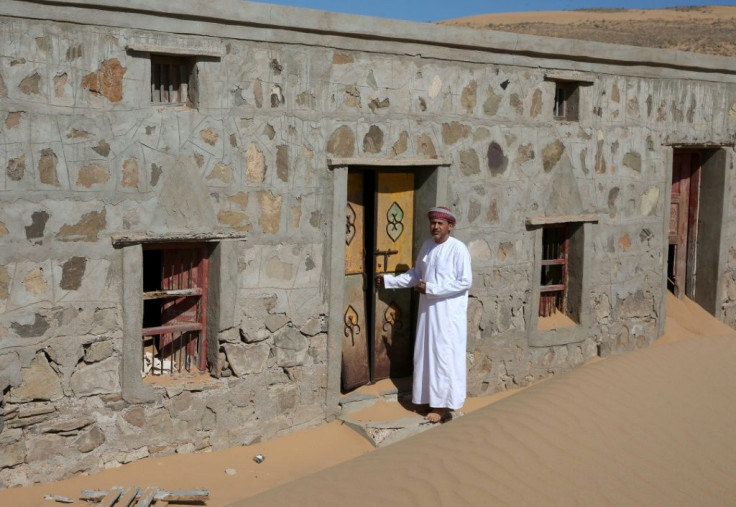 Mohammed al-Ghanbousi, a former inhabitant of Wadi al-Murr, stands next to his abandoned house in the sand-engulfed village