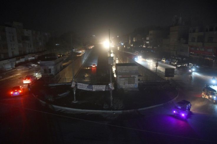 Motorists drive through a residential area during a power blackout in Pakistan's port city of Karachi early on January 10, 2021
