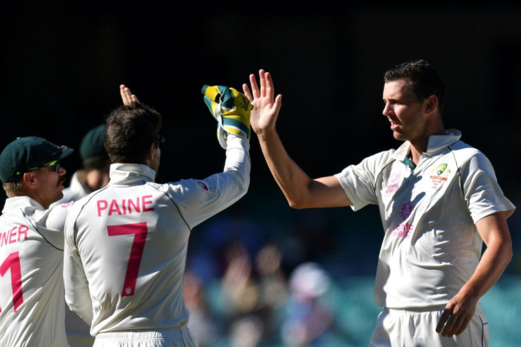 Australia's Josh Hazlewood (right) celebrates with teammates David Warner  and captain Tim Paine after taking the wicket of India's Shubman Gill
