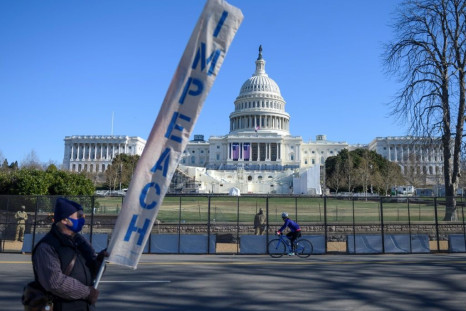 A protester carries a sign calling for Congress to impeach President Donald Trump near the US Capitol