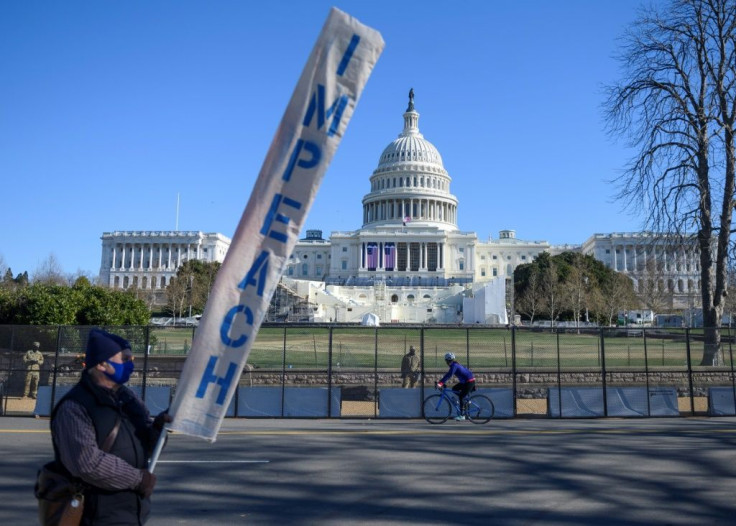 A protester carries a sign calling for Congress to impeach President Donald Trump near the US Capitol